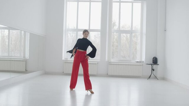 Young beautiful girl dancing ballroom dancing. A professional ballroom dancer is engaged in a large white hall.