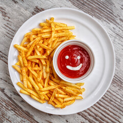 French fries with ketchup on wooden background.