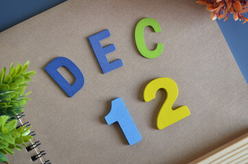 December 12, Cover design in natural concept with a brown notebook and colorful wooden alphabet.