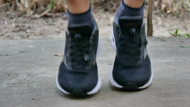 athletic feet with black sneakers jogging on concrete floor at home. Workout at home concept.