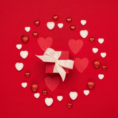 Red white hearts and gift box on red background. Valentines day concept. Flat lay, top view, copy space.