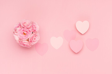 Flowers roses and  pink paper hearts on pink background. Valentines day concept. Flat lay, top view, copy space.
