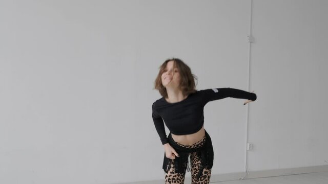Young beautiful girl dancing ballroom dancing. A professional ballroom dancer is engaged in a large white hall.