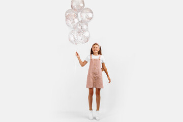 Full length photo of beautiful happy little girl holding balloons celebrating a festive event over isolated white background