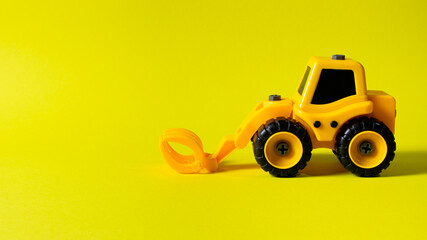 Children's construction machine lumber loader on a yellow background. Tractor for the boy and photo...