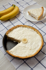 Homemade Tasty Banana Cream Pie on a white wooden table, low angle view.