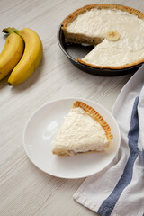 Piece of Homemade Tasty Banana Cream Pie on a white plate, low angle view.