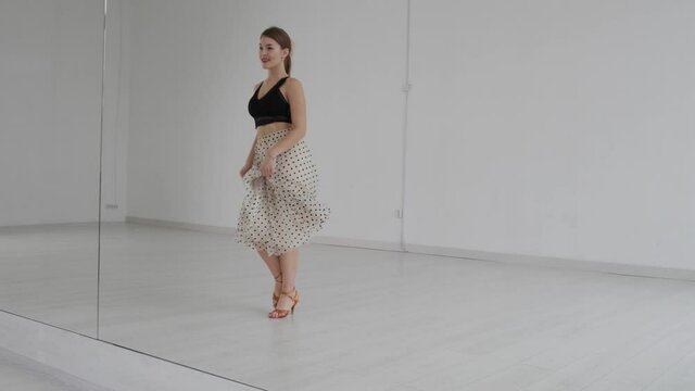Young beautiful girl dancing ballroom dancing. A professional ballroom dancer is engaged in a large white hall.