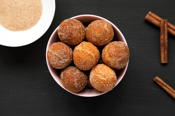 Homemade Fried Donut Holes in a pink bowl on a black surface, top view. Flat lay, overhead, from...