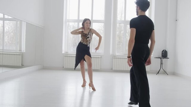 Young beautiful couple studying ballroom dance. A professional ballroom dancing couple dances in a large, bright, white hall