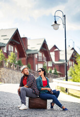couple in love sitting on road with suitcase