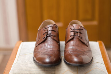 Pair of brown leather shoes stand on a chair, groom's accessories