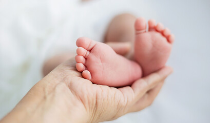 Obraz na płótnie Canvas Mother’s hands holding newborn baby feet. Closeup feet of newborn baby. Healthcare and medical love lifestyle father’s day background concept