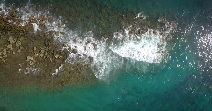Birds eye view of a rock breakwater and waves hitting against it