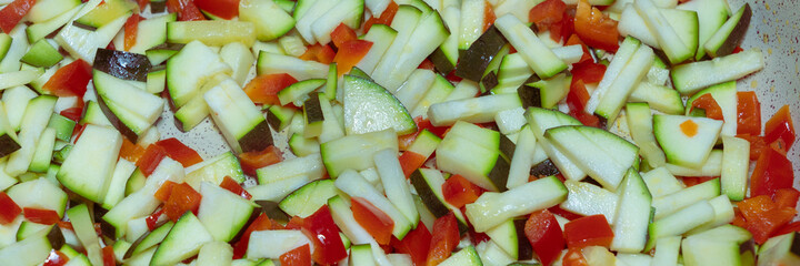 Zucchini and red peppers in pieces in a pan, banner