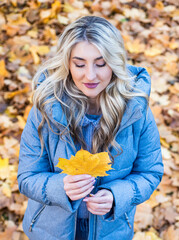 sexy lady in autumn warm clothes in fall forest or park with leaves, weather