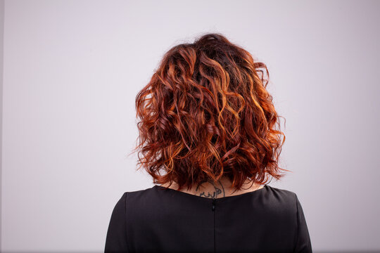 Back view portrait of beautiful curly dark red woman against white background