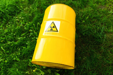 .The nuclear sign on a yellow metal barrel on the green grass. Radiation hazard symbol sign. Radioactive waste.