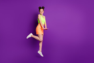 Fototapeta na wymiar Full length body size view of slim fit cheerful girl jumping enjoying free spare time posing isolated over bright violet color background