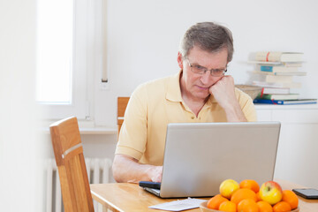 Mature tired man working with computer at home