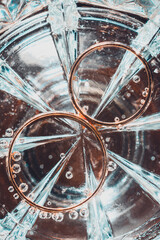 bridal rings on the bottom of a glass of water, bubbles and glitter of light.
