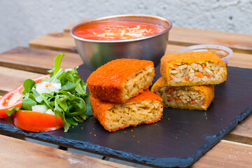 Classic, Italian arancini. deep fried Rice balls with minced meat and some vegetables inside. Tasty crunchy food with peanuts sauce and tomatoes soup with mozzarella cheese on the top. Close up view