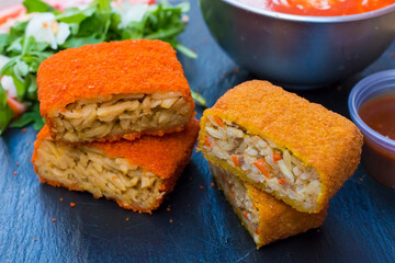 Classic, Italian arancini. deep fried Rice balls with minced meat and some vegetables inside. Tasty crunchy food with peanuts sauce and tomatoes soup with mozzarella cheese on the top. Close up view
