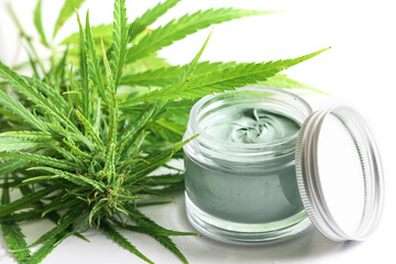  Green cannabis plant and jar with a moisturizing cream