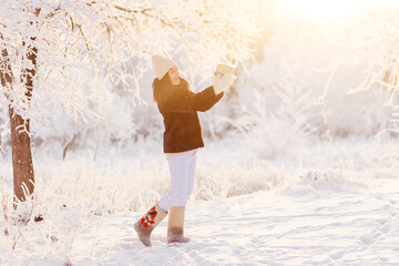 A young woman in a short fur coat and boots holds a beautiful gift in her hands in winter in a counter light
