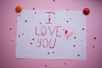 Lettering in red pencil I love you on a white sheet