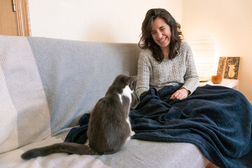 Attractive young woman playing with her cat at home