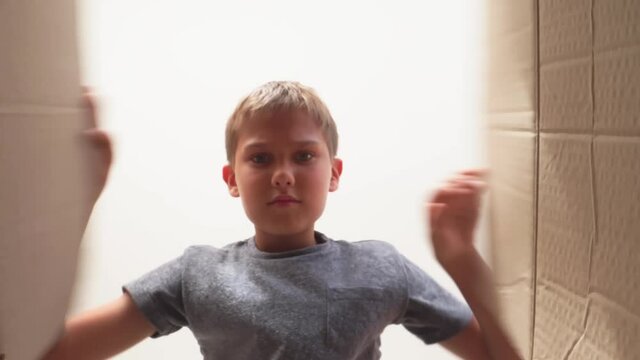 Frustrated, disappointed teenage boy open cardboard box and looking inside of package. Kid opens or unpacking present gift box. Sad, unsatisfied, angry, unhappy emotions. 4k video