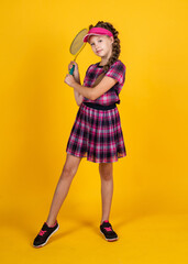 happy girl holding sport equipment. kid hold tennis racket. child wear fitness cap. childhood activity. healthy way of life. be energetic. badminton player with racquet