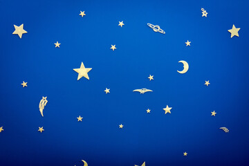 A night sky above bed of a young boy. There are stars and planets and pterosaurs.