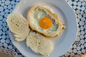 Egg fried in the middle of an slice of bread surrounded by crust and served with the remaining bread.