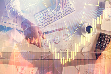 Multi exposure of man's hands typing over computer keyboard and forex graph hologram drawing. Top view. Financial markets concept.