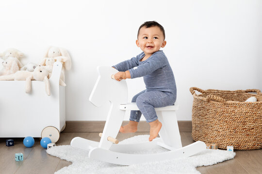 Smiling Baby On Rocking Horse In Playroom