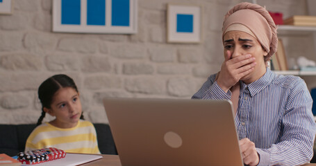 The headscarved woman working on the computer at home is making mistakes. The woman who made the...