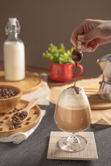 Obraz na płótnie Canvas iced latte coffee served with whipped cream topping and chocolate syrup in wine glass place on wooden table