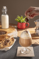 iced latte coffee served with whipped cream topping and chocolate syrup in wine glass place on wooden table