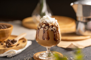 iced latte coffee served with whipped cream topping and chocolate syrup in wine glass place on wooden table
