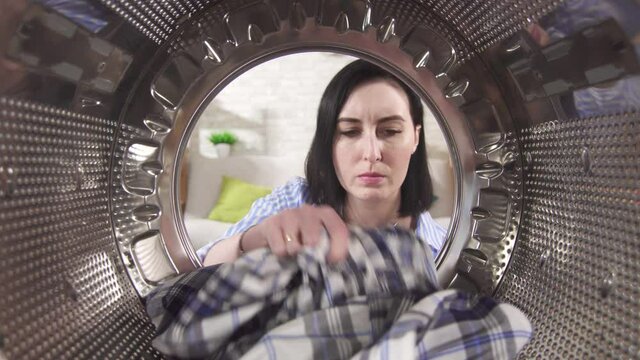 Young woman takes out her Laundry and smells a bad smell from the washing machine