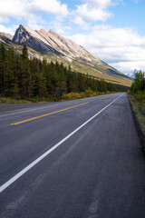 Blue sky with some clouds over a highway with a mountain chain in the background in British Columbia, Canada.