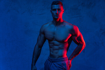 Muscular man posing in the colorful light