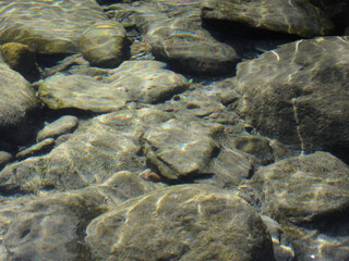 Nature background of transparent river water with stones
