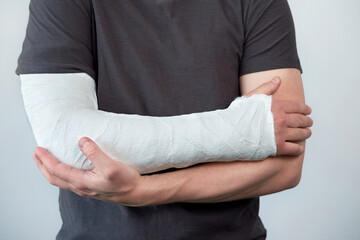 Closeup view of man's hand with plaster cast on a white wall background with copy space.