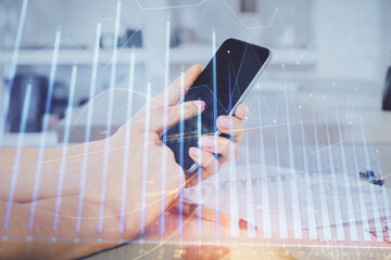 Double exposure of man's hands holding and using a digital device and forex graph drawing. Financial market concept.