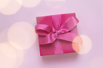 pink gift with christmas lights bokeh in front.