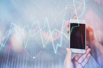 Double exposure of forex graph sketch hologram and woman holding and using a mobile device. Stock market concept.