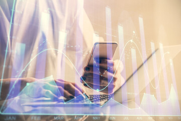 Double exposure of financial graph sketch hologram and woman holding and using a mobile device. Stock exchange concept.